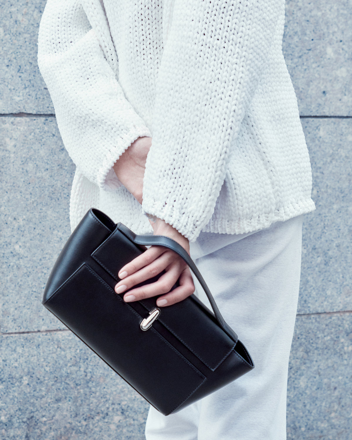 campaign on model image of a black leather bag with silver clasp