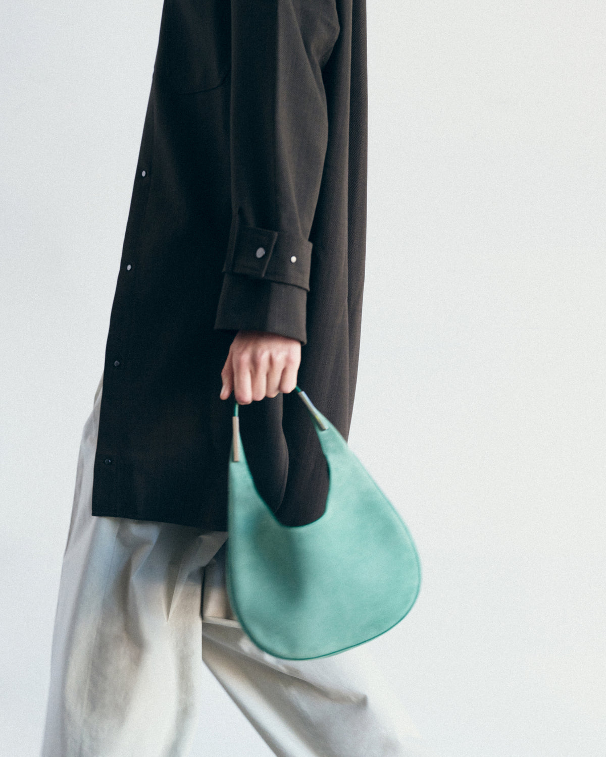 on model image of jade green suede bag with silver hardware on a white background