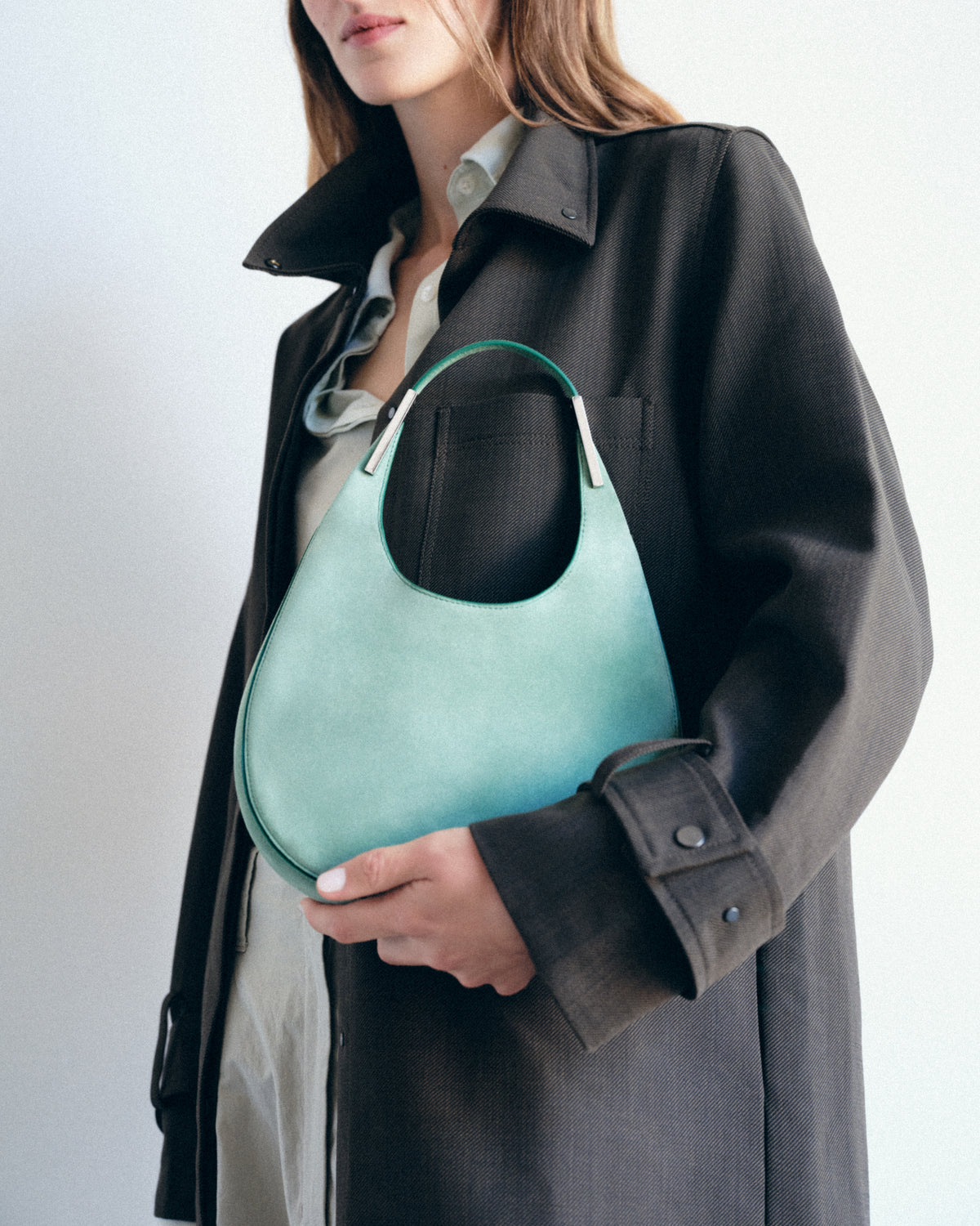 on model image of jade green suede bag with silver hardware on a white background