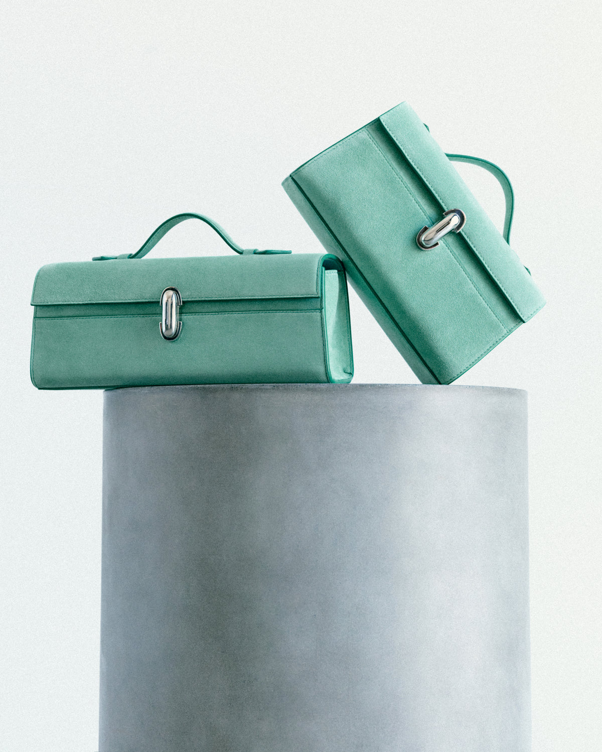 campaign image of two jade green suede bags with silver clasps on white background