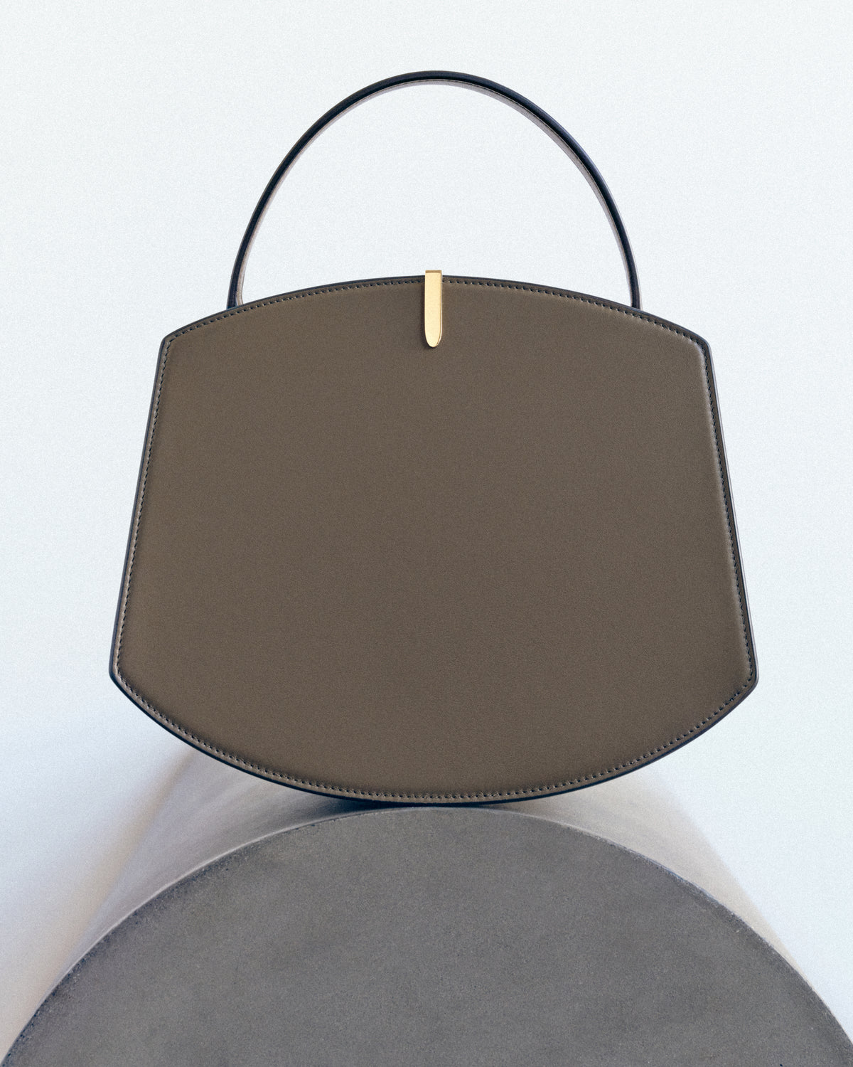 campaign image of brown leather bag with gold hardware on a white background