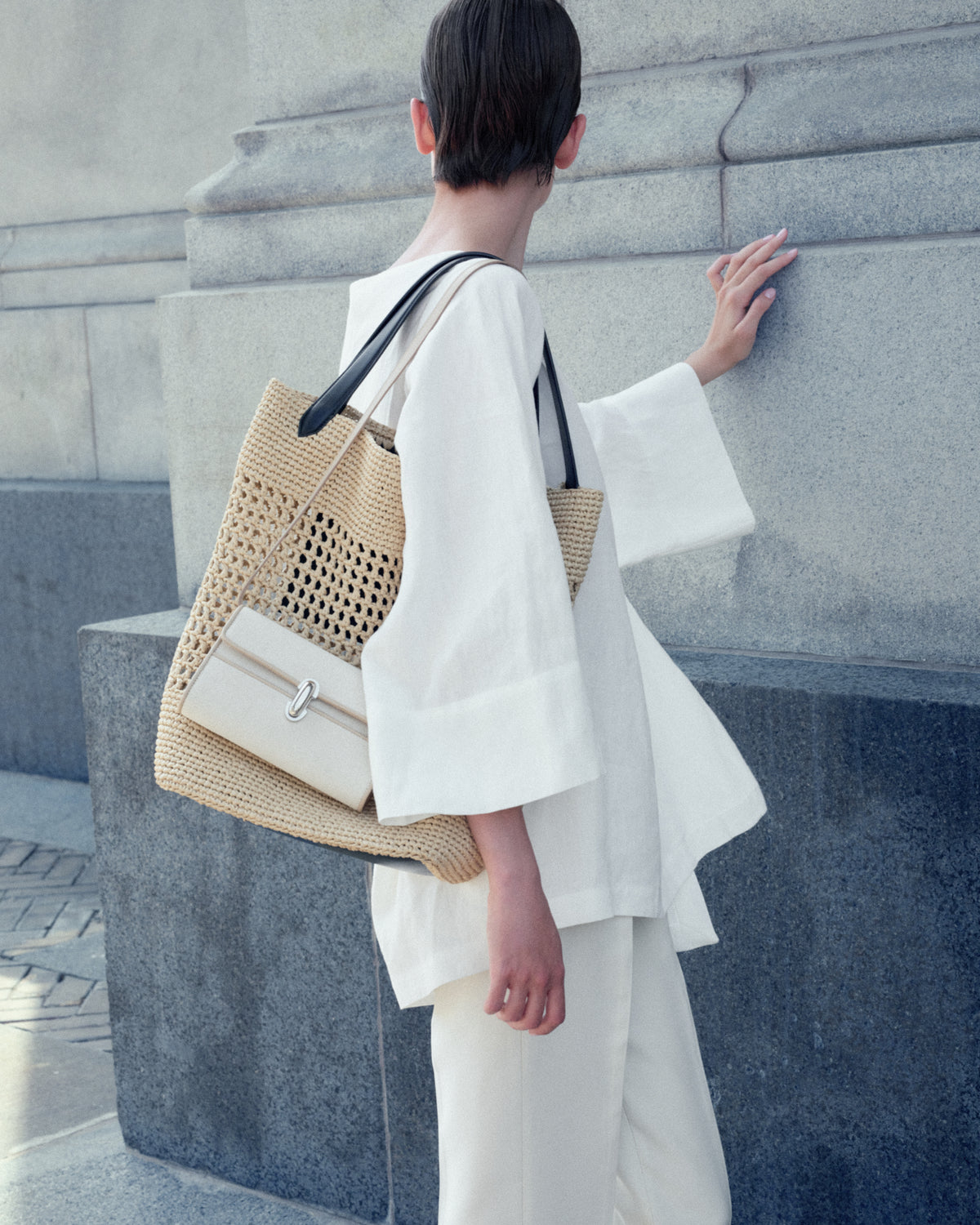 campaign on model image of a natural raffia tote and bone canvas bag with a silver clasp