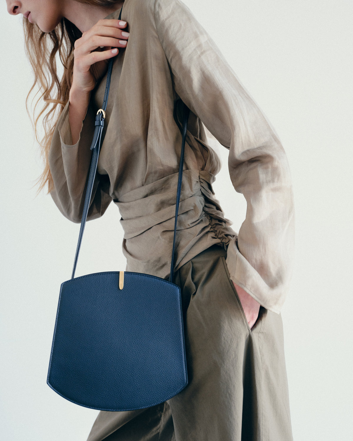 on model image of navy blue bag with gold hardware on a white background