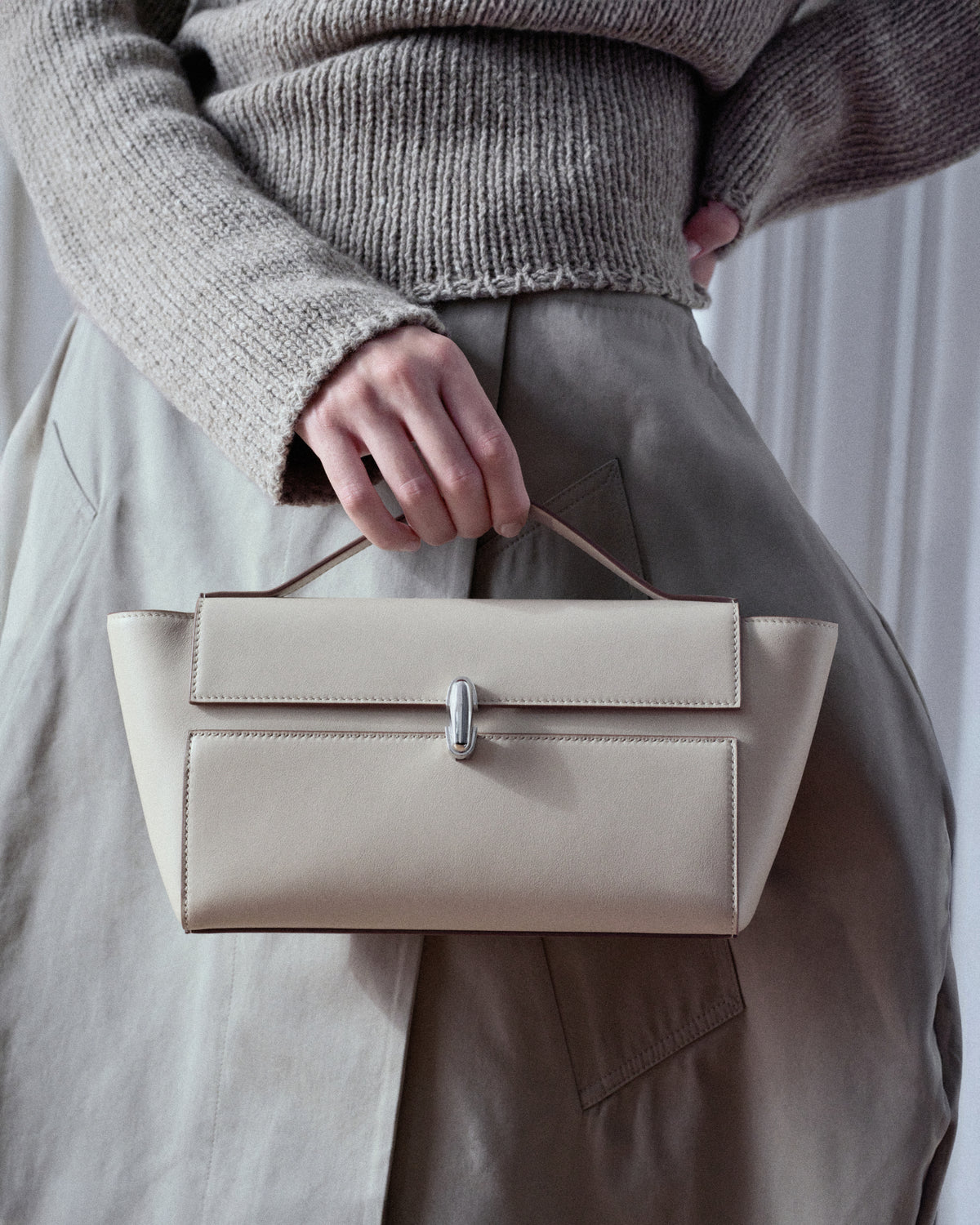 campaign on model image of a bone beige leather bag with silver clasp