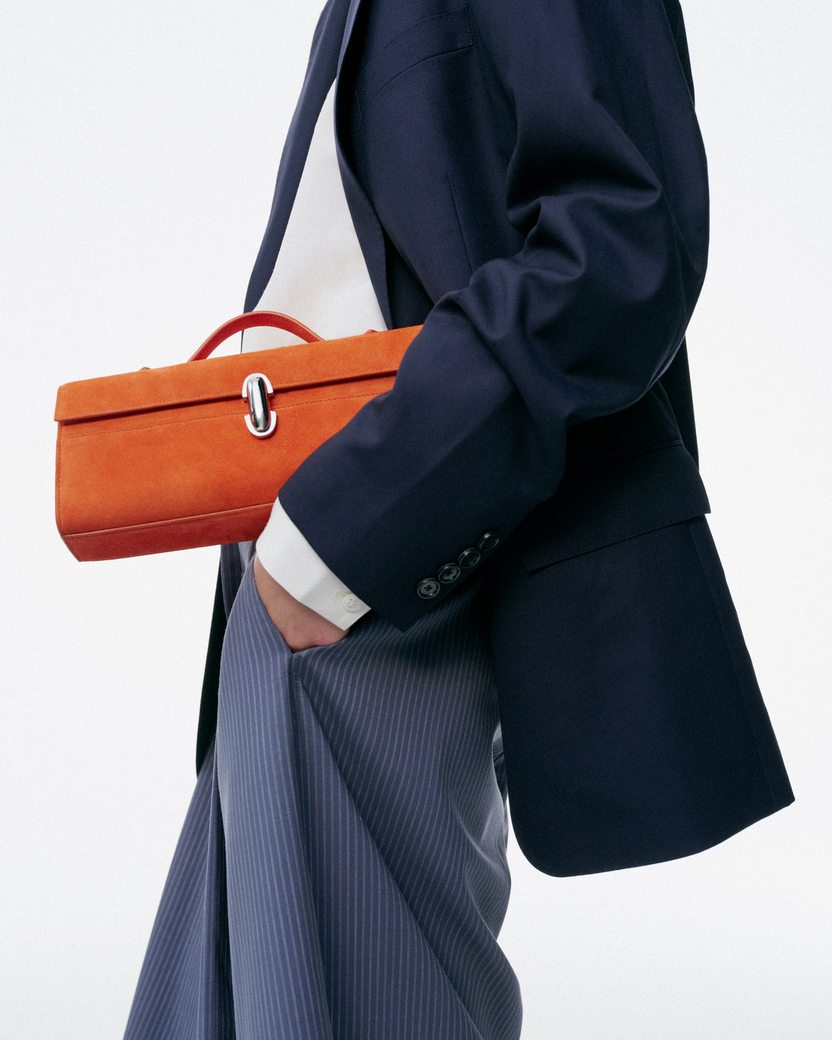 on model image of tangerine orange suede bag with silver clasp on a white background