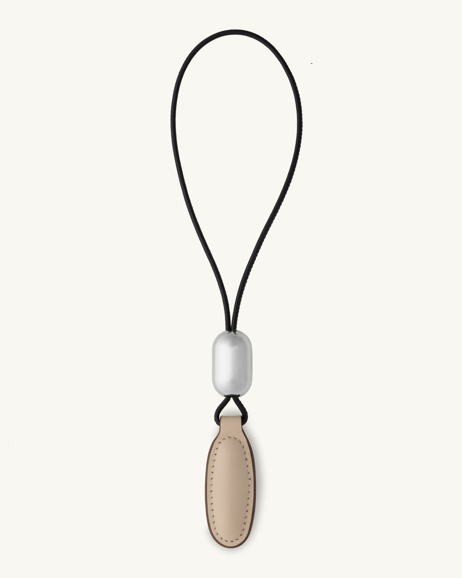 front view of a bone beige leather charm on a white background