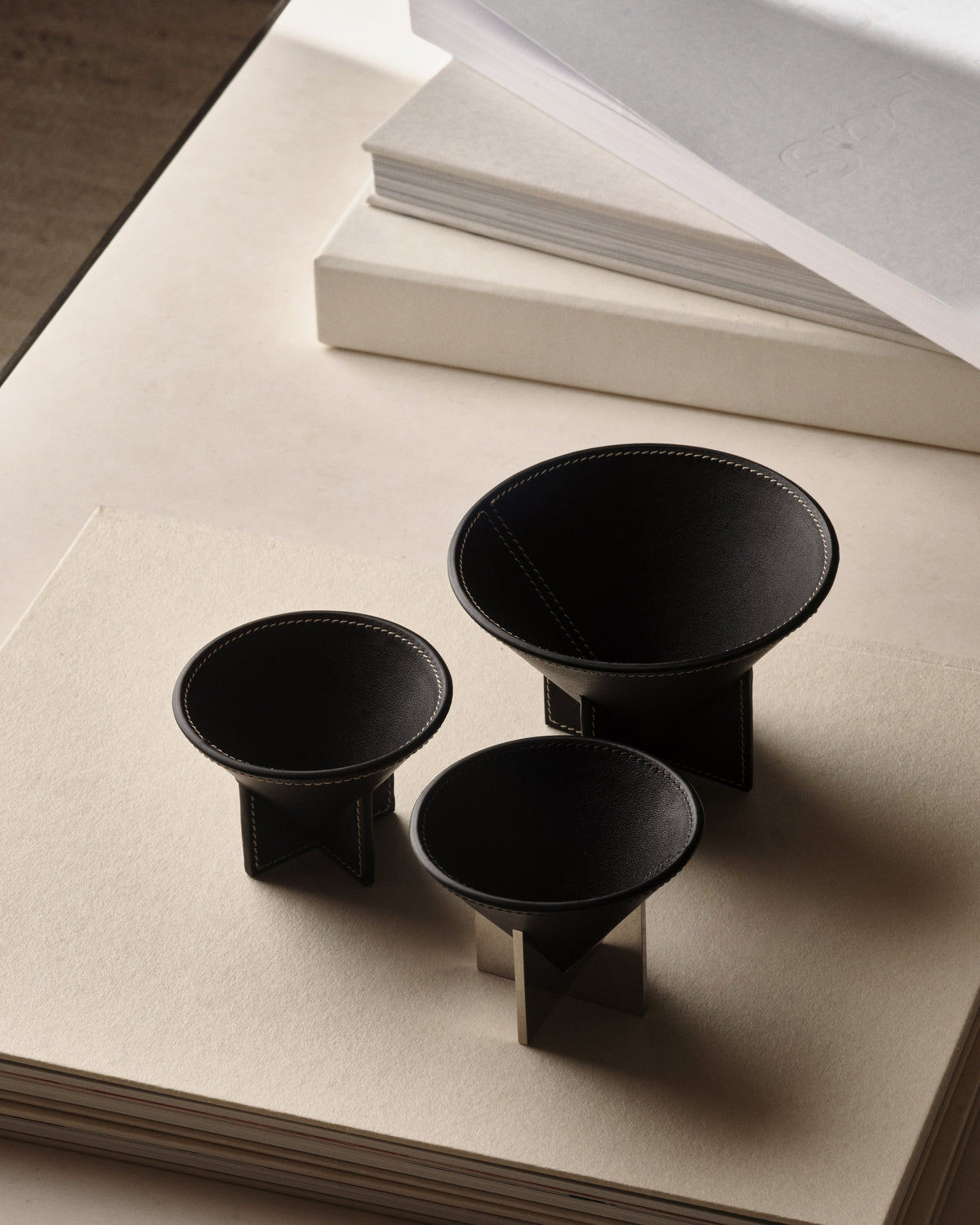 campaign image of three ebony black leather dishes on a coffee table
