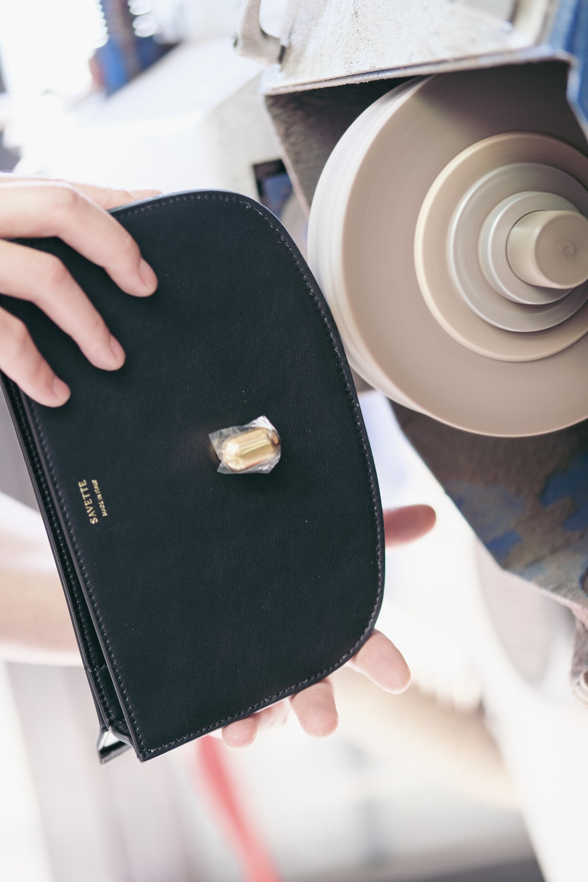 Man's hands using an edge painting machine while making a handbag